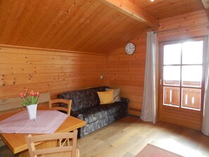 A wooden interior with a dining table, chairs, a sofa, and a clock on the wall. - Cozy Holiday Apartment Close to the Slopes (Kleinarl)