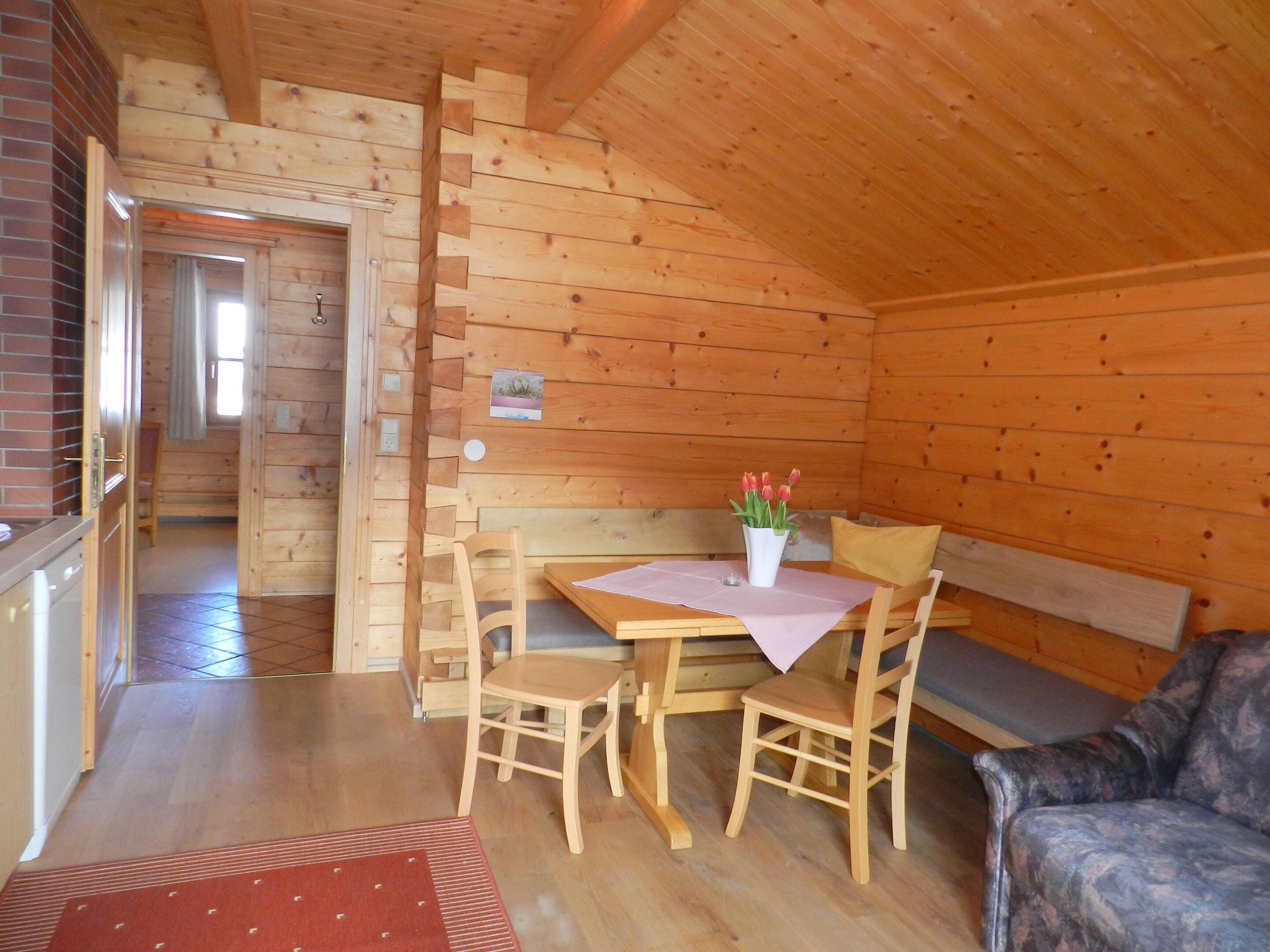 Un interior de madera con una mesa de comedor, sillas, un banco y un sofá.