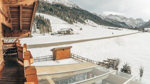 Een houten gebouw met een glazen balkon met uitzicht op een besneeuwd berglandschap.