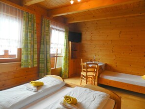 A wooden cabin room with two beds, a small table, and a chair. - Cozy Holiday Apartment Close to the Slopes (Kleinarl)