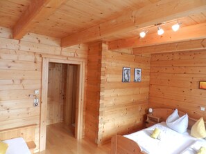 A wooden cabin room with a bed, a nightstand, and a wall-mounted light fixture. - Cozy Holiday Apartment Close to the Slopes (Kleinarl)