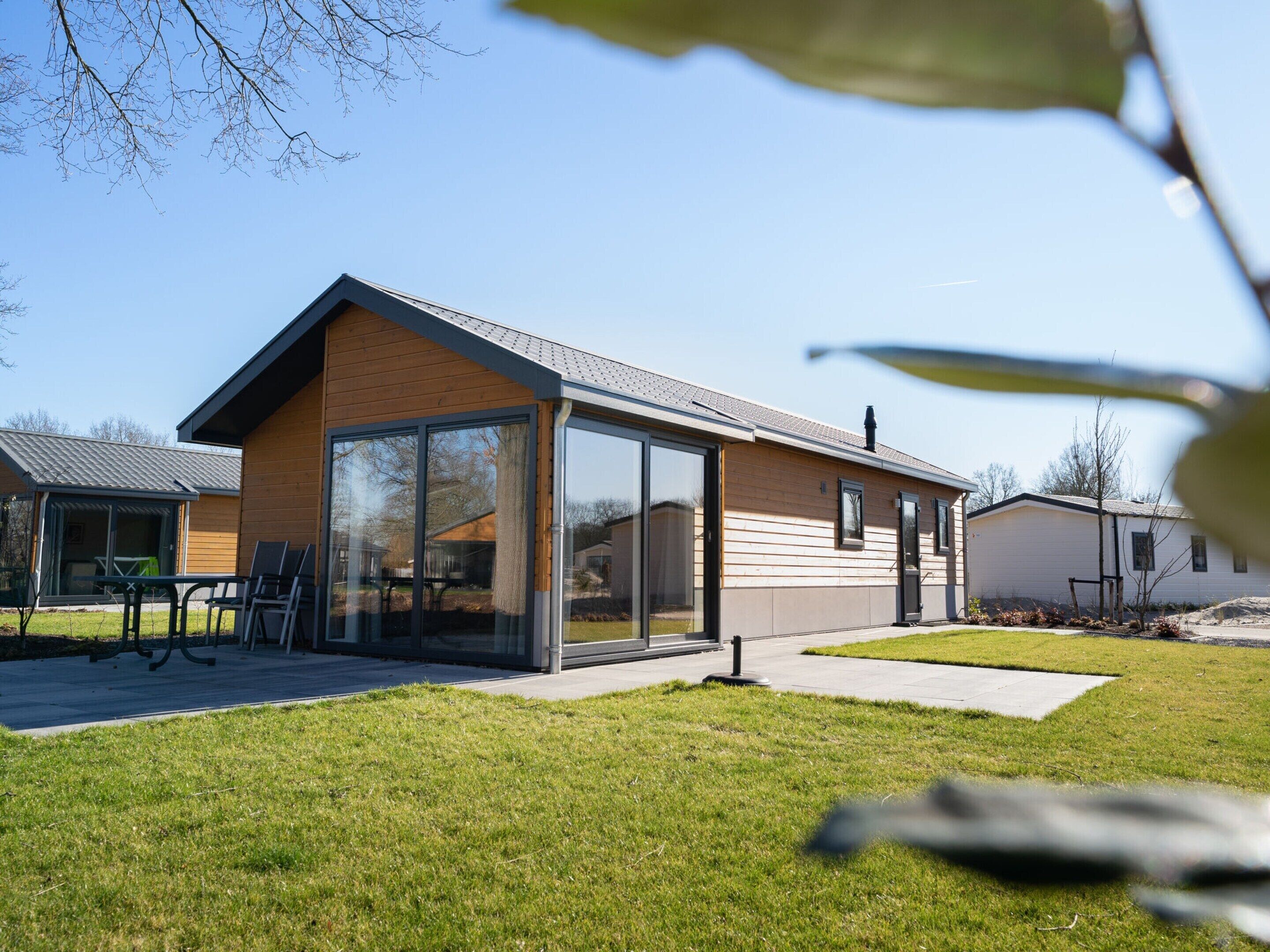 A modern single-story house with large glass windows, a flat roof, and a well-maintained lawn.