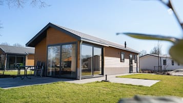 A modern single-story house with large glass windows, a flat roof, and a well-maintained lawn.