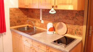 A kitchen with wooden cabinets, a granite countertop, a sink, a kettle, and a microwave. - Serene Apartment in Bohinjsko Jezero near Ski Lift (Bohinj)
