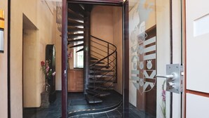 Um interior moderno com uma escadaria em espiral, uma área de recepção e uma porta de vidro decorativa.
