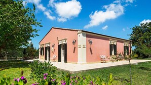 A pink building with a garden in front, featuring a bench and a small tree. - Belvilla by OYO Gira Sole (Syracuse)