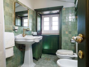 Une salle de bain avec un lavabo blanc, des toilettes et un miroir.