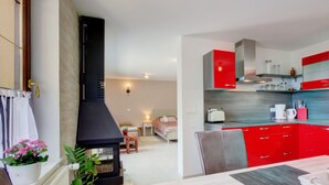 Une cuisine moderne avec des meubles de rangement rouges, une hotte noire et un coin repas comprenant une table et des chaises.