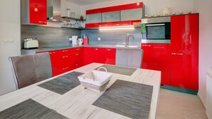 Une cuisine moderne avec des meubles de rangement rouges, un four à micro-ondes et un grille-pain.