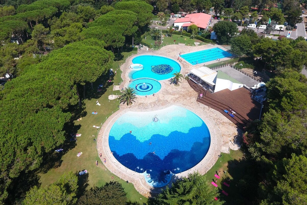 Luftaufnahme eines Resorts mit mehreren Schwimmbecken, umgeben von üppiger Vegetation und einigen Gebäuden.