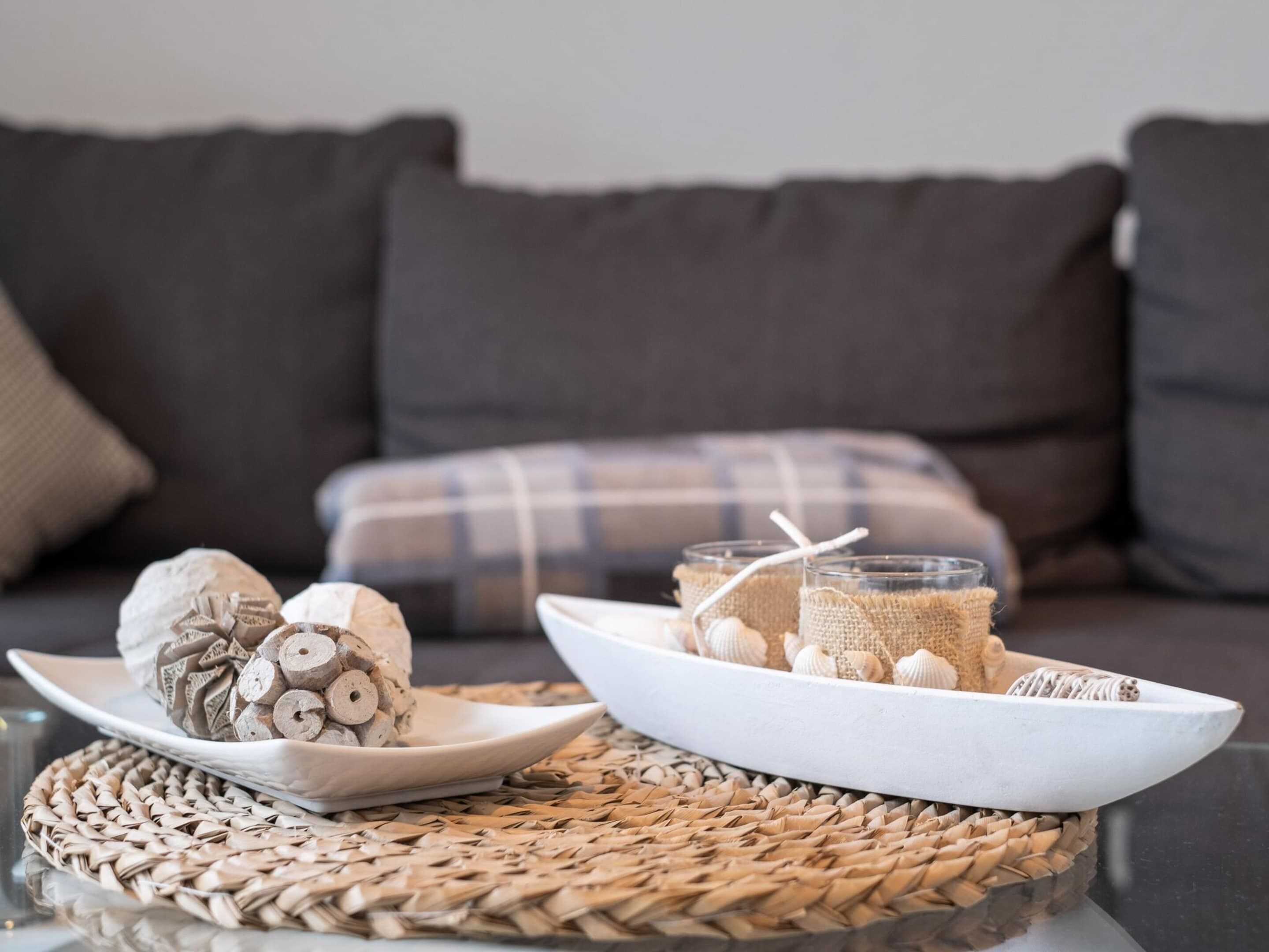A dining setup with a woven placemat, a plate with rolled items, and a glass with a burlap-wrapped item and a straw.