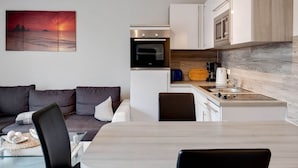 A compact living space with a kitchenette, a dining area, and a sofa. - Snug Apartment in Kalkhorst with Terrace near City Center (Kalkhorst)