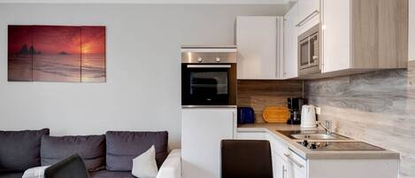 A compact living space with a kitchenette, a dining area, and a sofa.