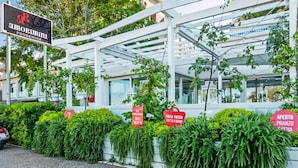 A restaurant named 'Amorimini Food & Wine' with a signboard, a white pergola structure, and green plants.