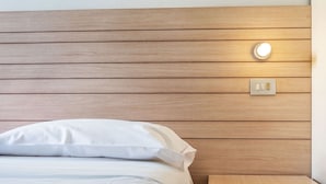 A neatly made bed with white linens and a wooden headboard.