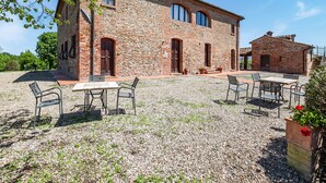 A rustic stone building with a gravel courtyard, outdoor seating, and a small garden area. - Scenic Farmhouse in Peccioli with Swimming Pool near Lakes (Peccioli)