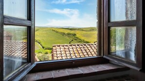 A window with a view of a green landscape and a tiled roof. - Scenic Farmhouse in Peccioli with Swimming Pool near Lakes (Peccioli)