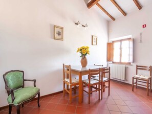A dining area with a table, chairs, a vase of flowers, and a window with blinds.