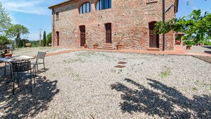 A stone building with a gravel courtyard, outdoor seating, and a view of the countryside. - Scenic Farmhouse in Peccioli with Swimming Pool near Lakes (Peccioli)