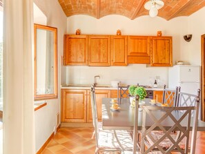 A kitchen with wooden cabinets, a dining table with chairs, and a refrigerator.