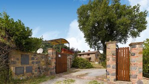 A stone-walled entrance with a wooden gate, a covered area, and a pathway leading to a building. - Belvilla by OYO Piandigoro - Le Querce (Radicofani)