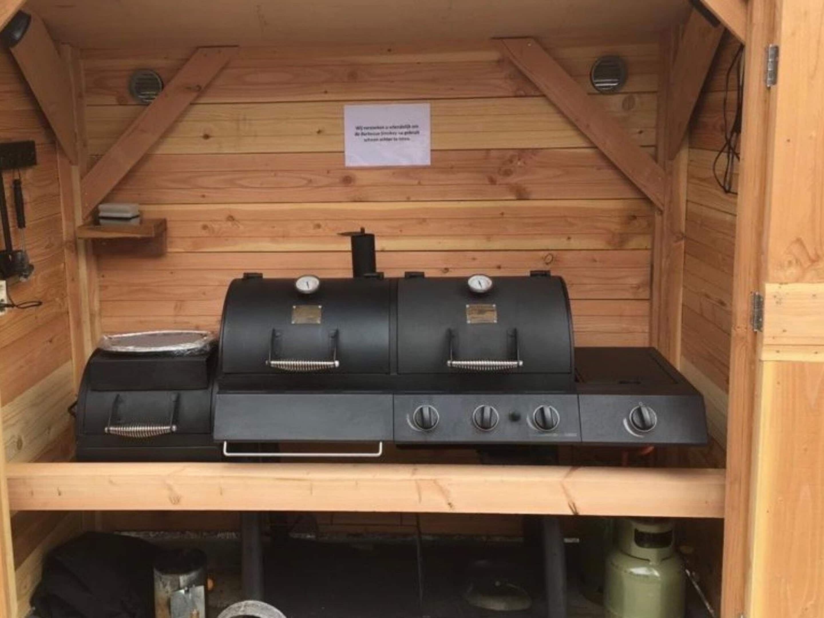 Una estructura de madera con una parrilla para barbacoa y un tanque de gas.
