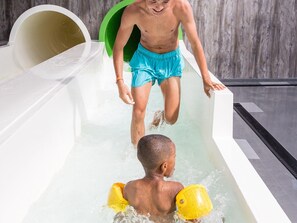A man in a bathtub with a child, both wearing swimwear. - Fully Furnished Tiny House near Beach (Maurik)