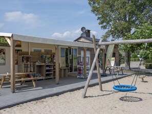 A wooden structure with a swing set and a sandpit, likely a children's play area. - Fully Furnished Tiny House near Beach (Maurik)