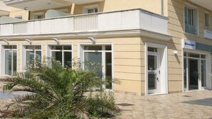 Un immeuble à plusieurs étages doté de balcons, d’un distributeur automatique de billets bien visible et d’une enseigne indiquant « Valmare ».