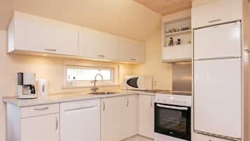 A modern kitchen with white cabinetry, a Bosch refrigerator, a Bosch oven, a Bosch coffee maker, and a window above the sink.