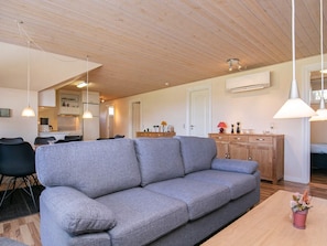 A modern living room with a grey sofa, wooden dining table, and pendant lighting. - 6 Person Holiday Home in Humble (Sydlangeland)