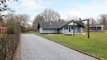 A gravel driveway leading to a single-story building with a sloped roof and a porch.