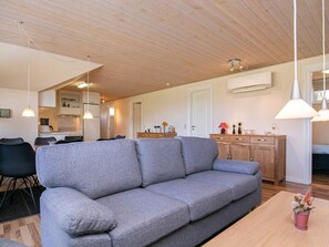 A modern living room with a grey sofa, wooden dining table, and pendant lighting. - 6 Person Holiday Home in Humble (Sydlangeland)