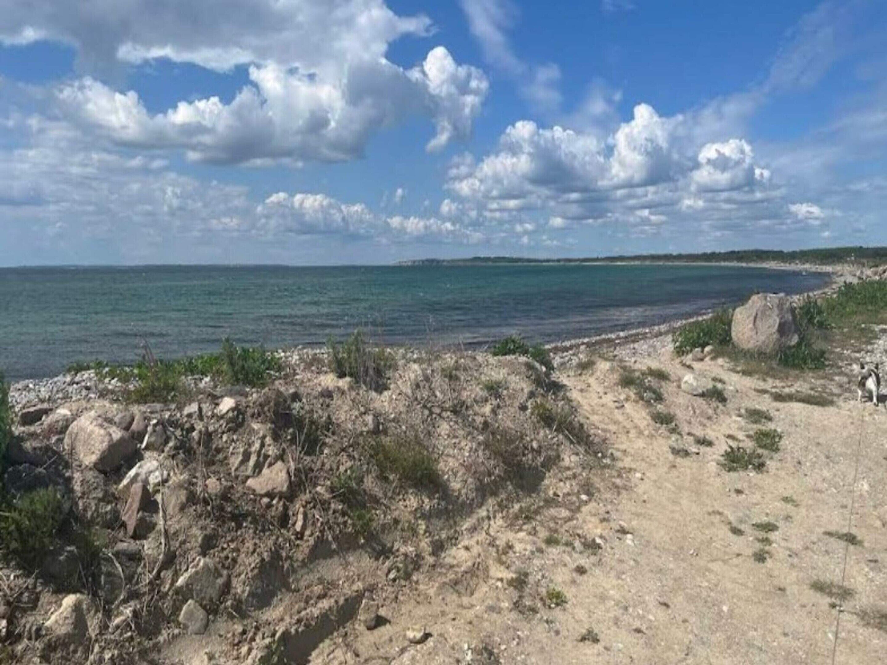 Eine Küstenlandschaft mit felsiger Küste, blauem Himmel und Blick auf das Meer.