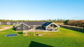 A row of modern houses with a well-maintained lawn, a swing set, and a trampoline. - Holiday Home in Nørre Nebel (Norre Nebel)