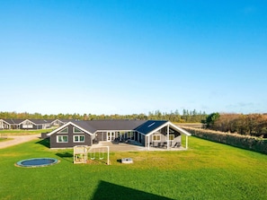 A row of modern houses with a well-maintained lawn, a swing set, and a trampoline. - Holiday Home in Nørre Nebel (Norre Nebel)