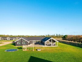 Una hilera de casas modernas con un césped cuidado, un columpio y un trampolín.
