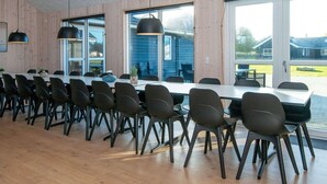 A long dining table with chairs, large windows, and pendant lights. - Holiday Home in Nørre Nebel (Norre Nebel)