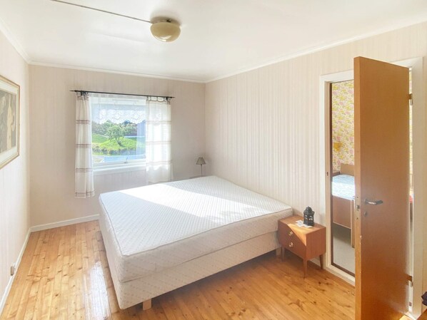 A bedroom with a single bed, a bedside table, a lamp, a window with curtains, and a door. - 10 Person Holiday Home in Brekke (Gulen)