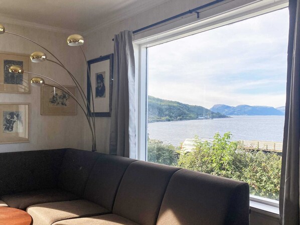 A room with a large window, a sofa, and framed pictures on the wall. - 10 Person Holiday Home in Brekke (Gulen)