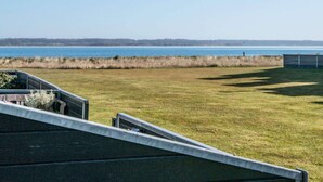 A view of a grassy area with a body of water in the background. - Holiday Home in Juelsminde (Juelsminde)