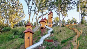 A playground with a slide, wooden towers, and a wooden staircase. - Holiday Home in Juelsminde (Juelsminde)