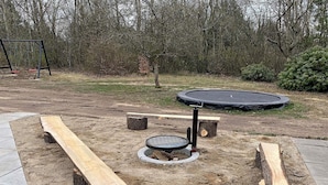A playground with a swing set, a trampoline, and a circular play area with a central pole.
