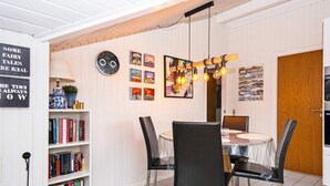 A dining area with a round table, black chairs, and a wooden ceiling.