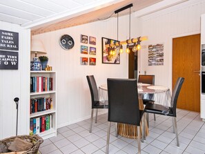 A dining area with a round table, black chairs, and a wooden ceiling.