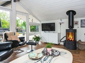 Una sala de estar moderna con chimenea, muebles de cuero, televisor y vistas al exterior.
