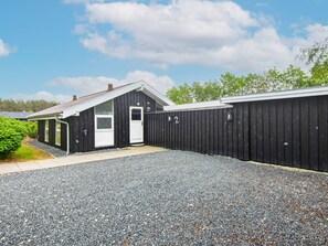 A building with a black exterior, a white door, and a gravel driveway.
