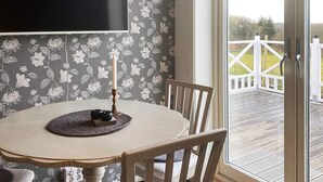 A dining area with a table, chairs, a candle, and a TV mounted on the wall. - 4 Person Holiday Home in Farjestaden (Farjestaden)