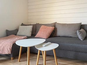A modern living room with a grey sofa, a white coffee table, and a remote control on the table. - 4 Person Holiday Home in Farjestaden (Farjestaden)