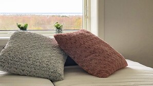 A bed with three pillows and a view of a forest through a window. - 4 Person Holiday Home in Farjestaden (Farjestaden)